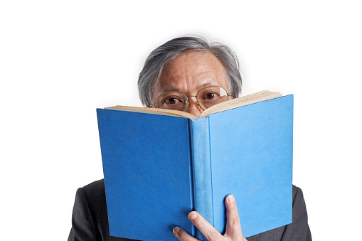 senior chinese man with formal wear eyeglasses reading book against white background