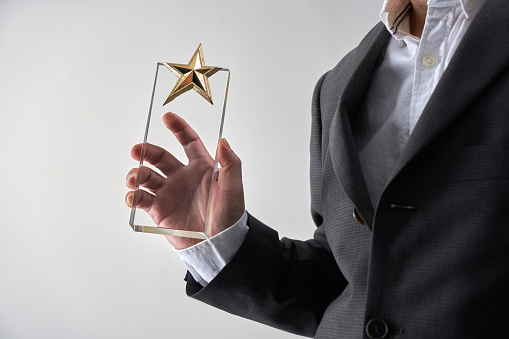mid section of man with formal wear holding star glass trophy