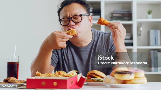 Asian Fat Man Enjoy To Eat Unhealthy Junk Food Hamburger Pizza Fried Chicken Stock Photo - Download Image Now