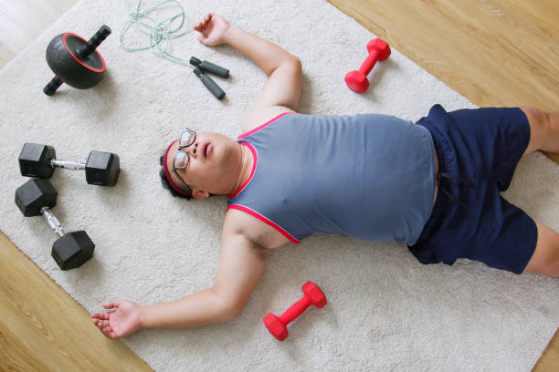 Fat middle-aged exhausted asian man in sportswear workout with sit up at home stock photo