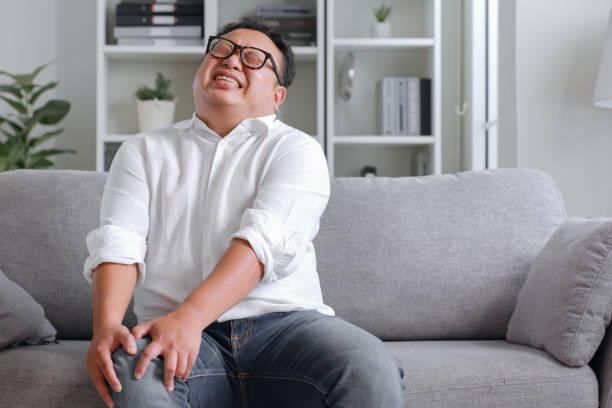 istock Oversized Asian man suffering from knee pain at home 1435606398