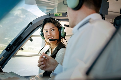 Female trainee pilot listening to instructor during a flight simulation training. Woman learning to fly helicopter with instructor inside a flight simulator.