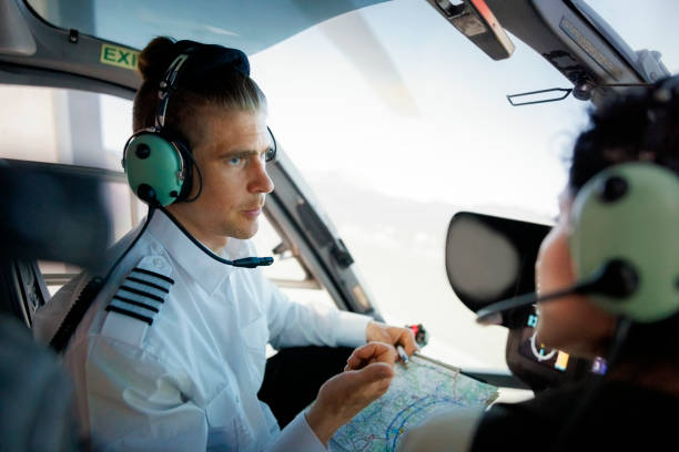 istock Male pilot talking with co-pilot holding route map during flight 1435607924