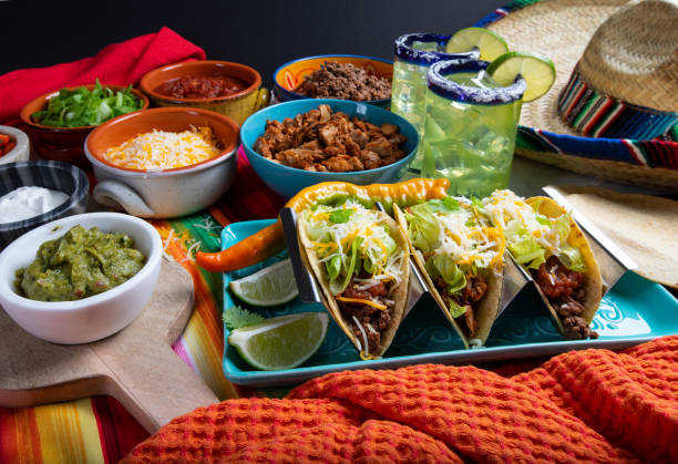 Taco lifestyle meal with food ingredients for friends, family Tacos with all the Trimmings like chicken, Beef, Sour Cream and Cheese on a Rustic Background to be Served in a Restaurant with Sombrero with Margaritas mexican food stock pictures, royalty-free photos & images