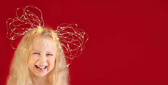 Little laughing blonde girl with bow of  Christmas lights