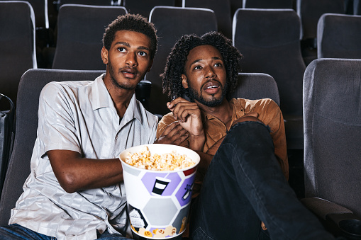 Gay couple in a movie theater enjoying a movie together.