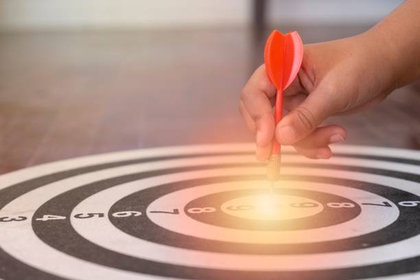 istock Closeup of a hand holding a dart over the target with a light 1435617780