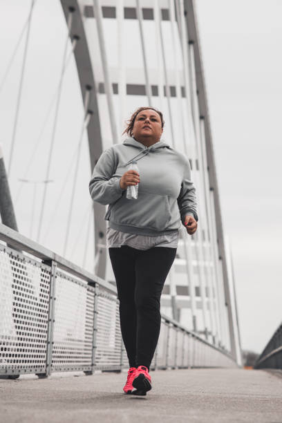 istock Obese Hispanic woman running on a bridge 1435624724