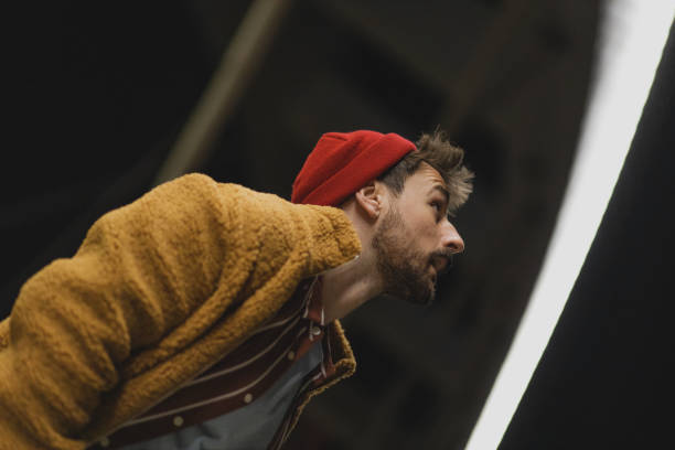 Handsome and modern young man dressed as a hipster, standing on a bridge alone at night.