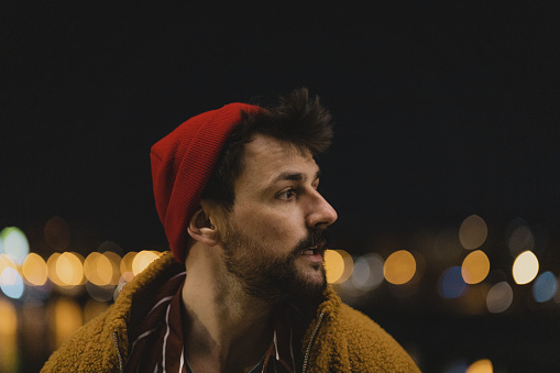 Close-up of a handsome young man dressed like a modern hipster at night.