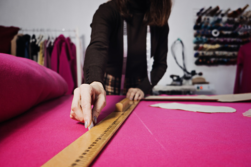 Conscious Clothing, zero-waste, zero-sweatshop fashion. Sewing sustainable fashion industry. Seamstress working with clothing and sewing pattern on table in tailor shop