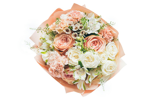 Close-up of peach and white roses in a bouquet on a wooden surface. Concept of expressing love, gratitude, sympathy or congratulations with a beautiful floral gift.