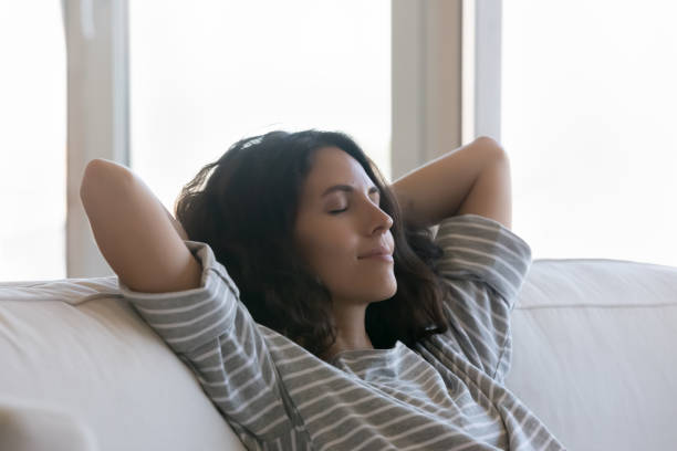istock Beautiful woman relaxing on sofa with hands behind head, closeup 1435630986