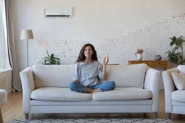 istock Attractive Hispanic woman holds remote controller turns on AC 1435630989