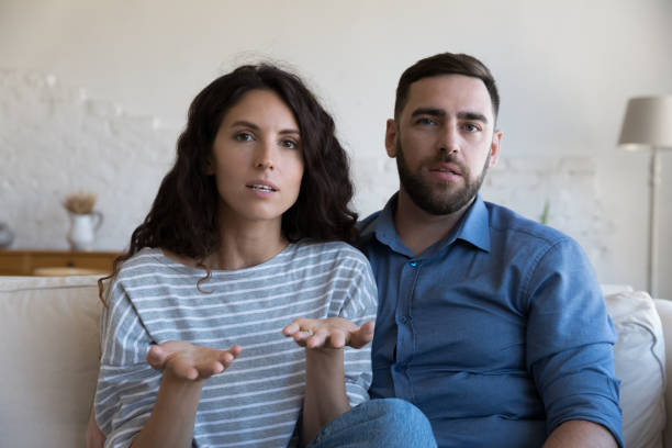 Serious couple look at camera having videocall conversation