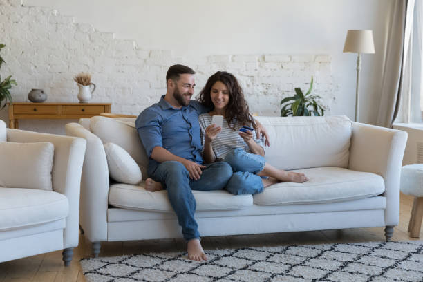 istock Couple enjoy e-shopping at home using smartphone and credit card 1435631355