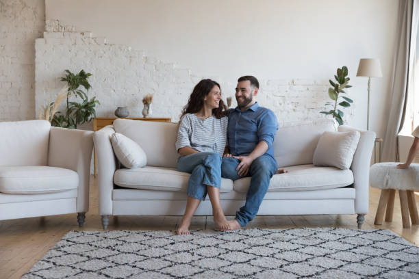 istock Smiling couple sit on sofa enjoy pleasant talk at home 1435631737