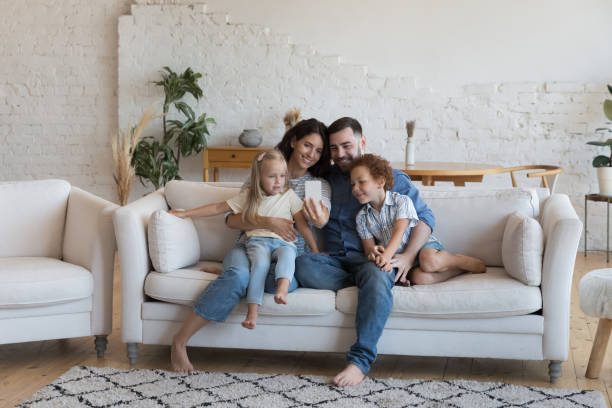 istock Smiling young family with children using smart phone 1435632977