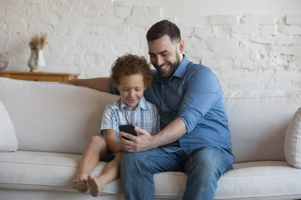 istock Dad and son use cellphone seated on couch at home 1435632979