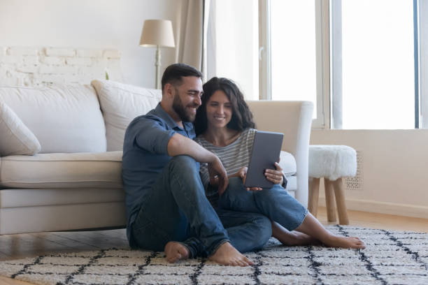 istock Millennial couple using digital tablet seated on floor at home 1435633175