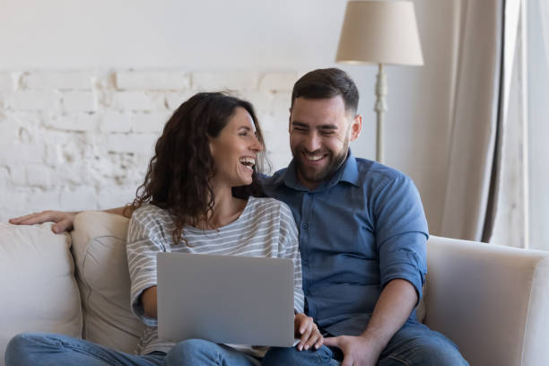 istock Millennial spouses laughing sit on sofa with laptop 1435633642
