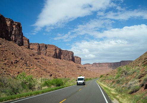 White van driving on empty road in Utah , USA