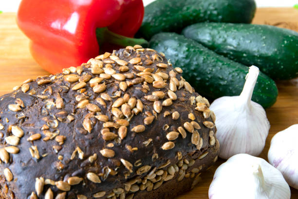 Rye bread with sunflower seeds on a chopping board with vegetables close-up. The concept of healthy eating.