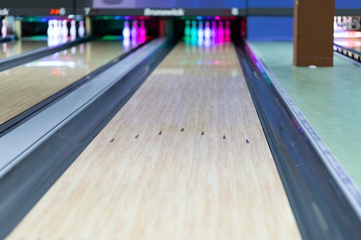 Close-up on a man bowling and holding a ball at the alley - sports and recreation concepts