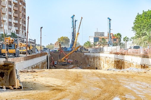 Cheraga, Algiers Algeria - October 10, 2022: National road RN 41 with construction machinery, trucks, diggers, cranes and workers in the underground dusty dug up road.