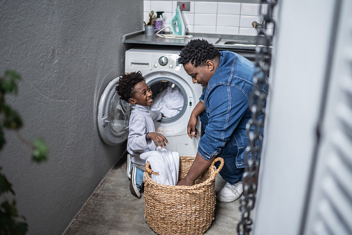 Father and son washing clothes in the laundry at home