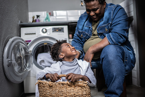 Father and son playing on a basket in the laundry at home