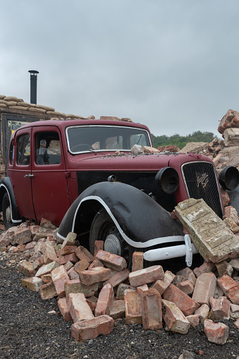 Tarrant Hinton.Dorset.United Kingdom.August 25th 2022.A scrap Austin six is half buried amongst rubble to replicate a typical scene from world war two