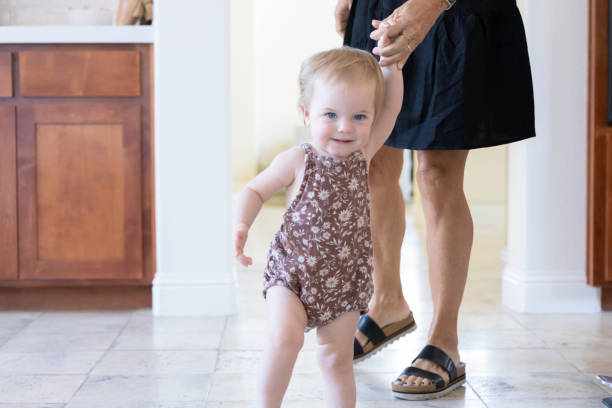 istock One year old female toddler learning to walk while holding hands with grandma 1435655352