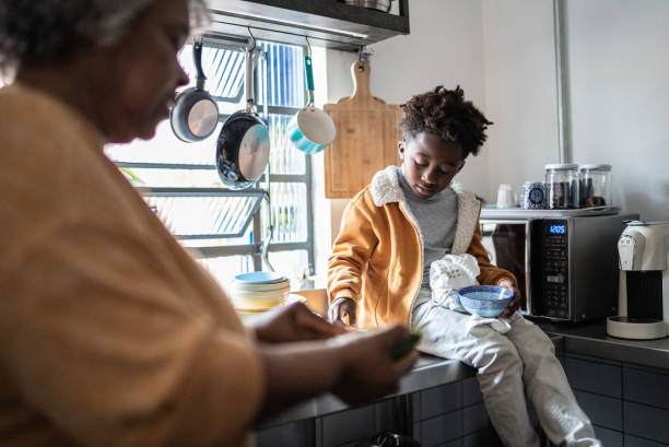 Grandson helping grandmother cooking in the kitchen at home