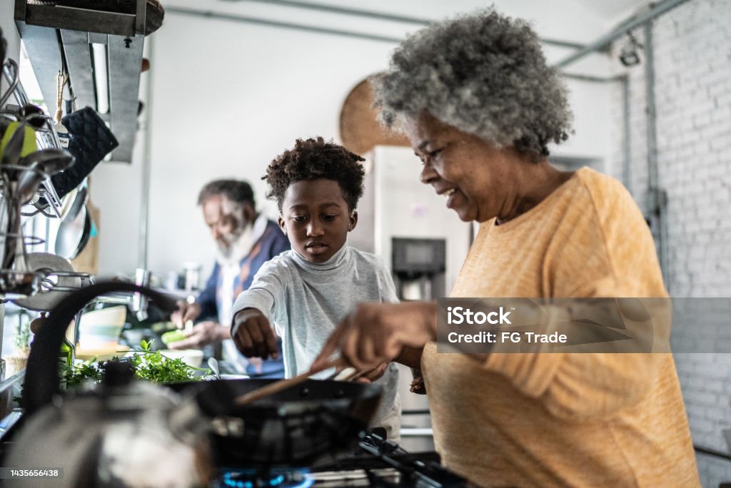 Grandson helping his grandmother cooking at home Family Stock Photo