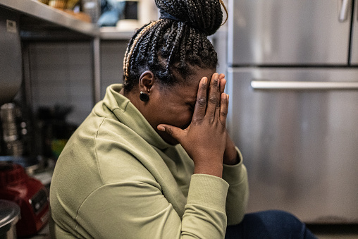 Sad mid adult woman in the kitchen at home