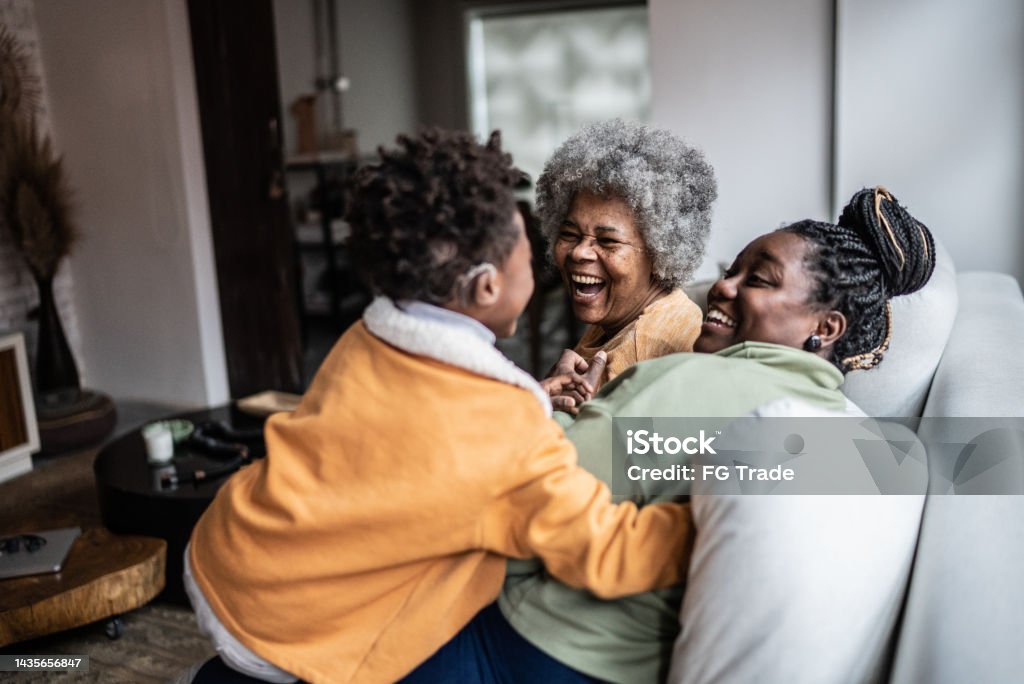 Child playing with his mother and grandmother in the living room at home Family Stock Photo
