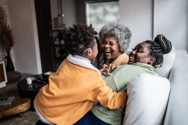ребенок играет с мамой и бабушкой в гостиной дома - grandmother senior adult smiling women стоковые фото и изображения