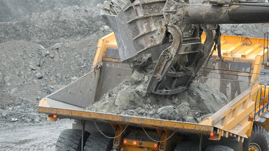 Close-up of excavator loading the dumper with ore in the quarry. Mining industry