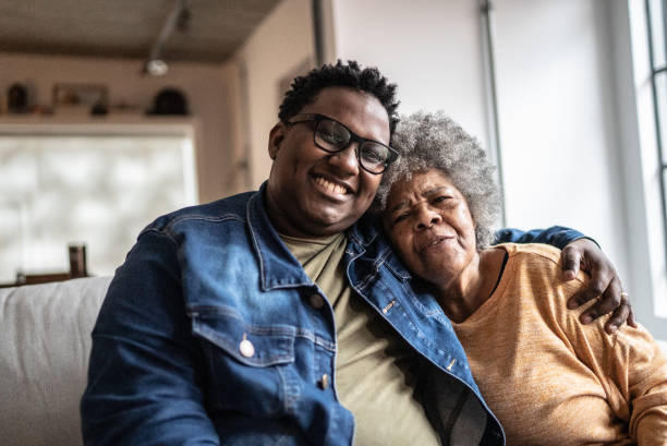 portrait of mother and son emnbracing in the living room at home - family senior adult healthy lifestyle happiness imagens e fotografias de stock