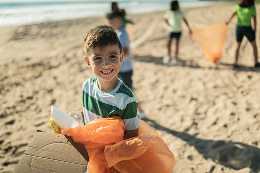 Portrait of boy with plastics and cardboard at the beach