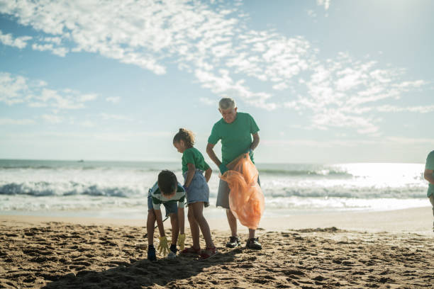 istock Senior man helping children pick up garbage at the beach 1435661881