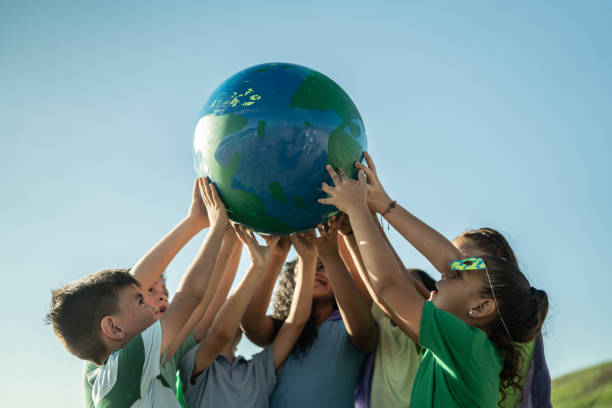 niños sosteniendo un planeta al aire libre - día de la tierra fotografías e imágenes de stock