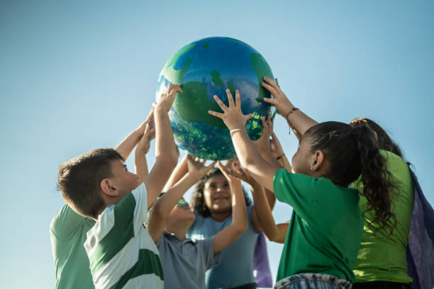 niños sosteniendo un planeta al aire libre - futuro sostenible fotografías e imágenes de stock