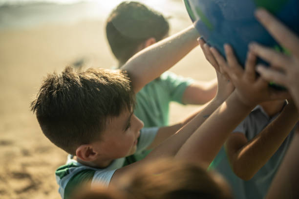 istock Boy holding a planet with other children at the beach 1435661960