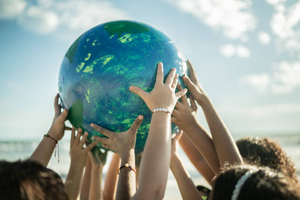 primer plano de niños sosteniendo un planeta en la playa - environment fotografías e imágenes de stock