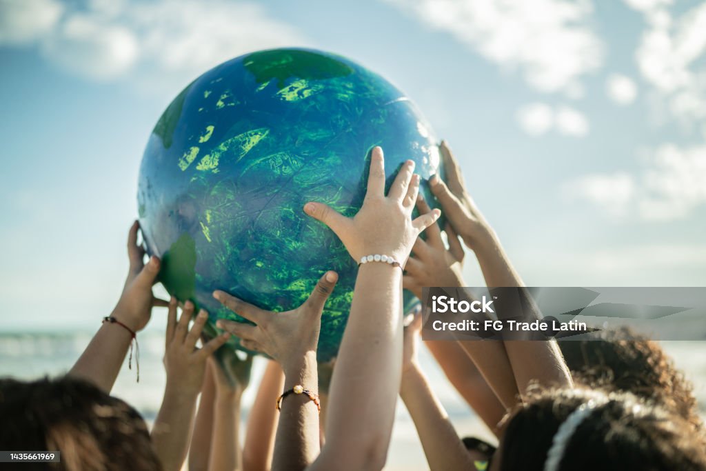 Close-up of children holding a planet at the beach Sustainable Resources Stock Photo