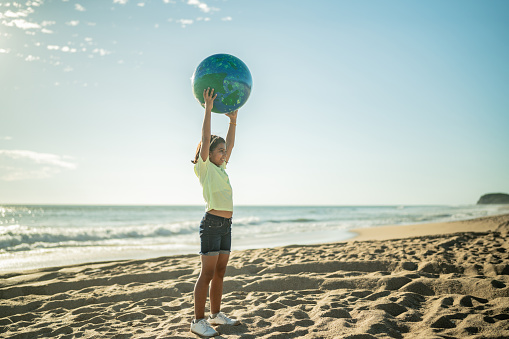 Girl holding a planet sphere at the beach