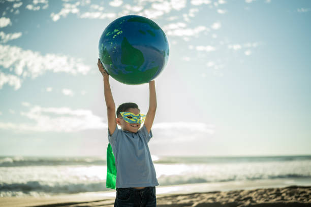 istock Superheroe boy holding an earth sphere at the beach 1435662039
