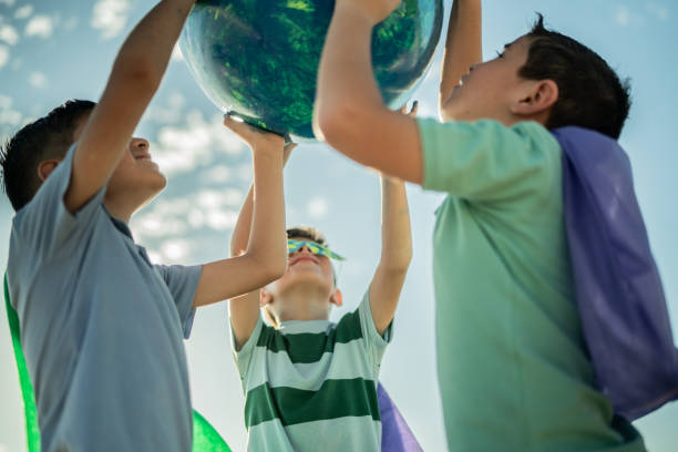 istock Boys holding an earth sphere at the beach 1435662069